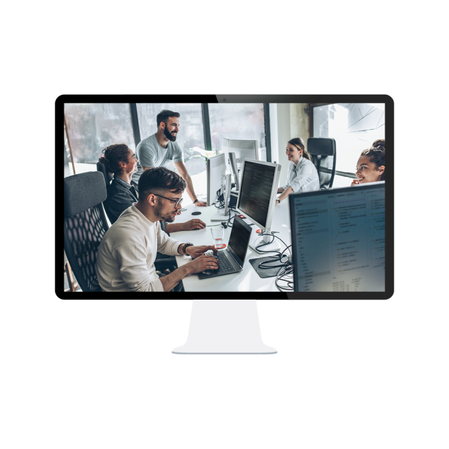 A group of workers around a large table with computers and laptops in front of them. 