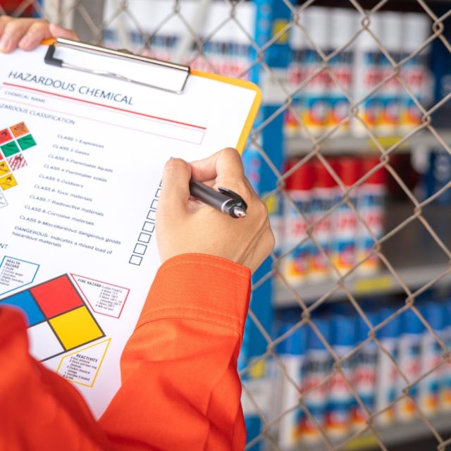 Employee with clipboard checking off hazardous chemicals on a list.